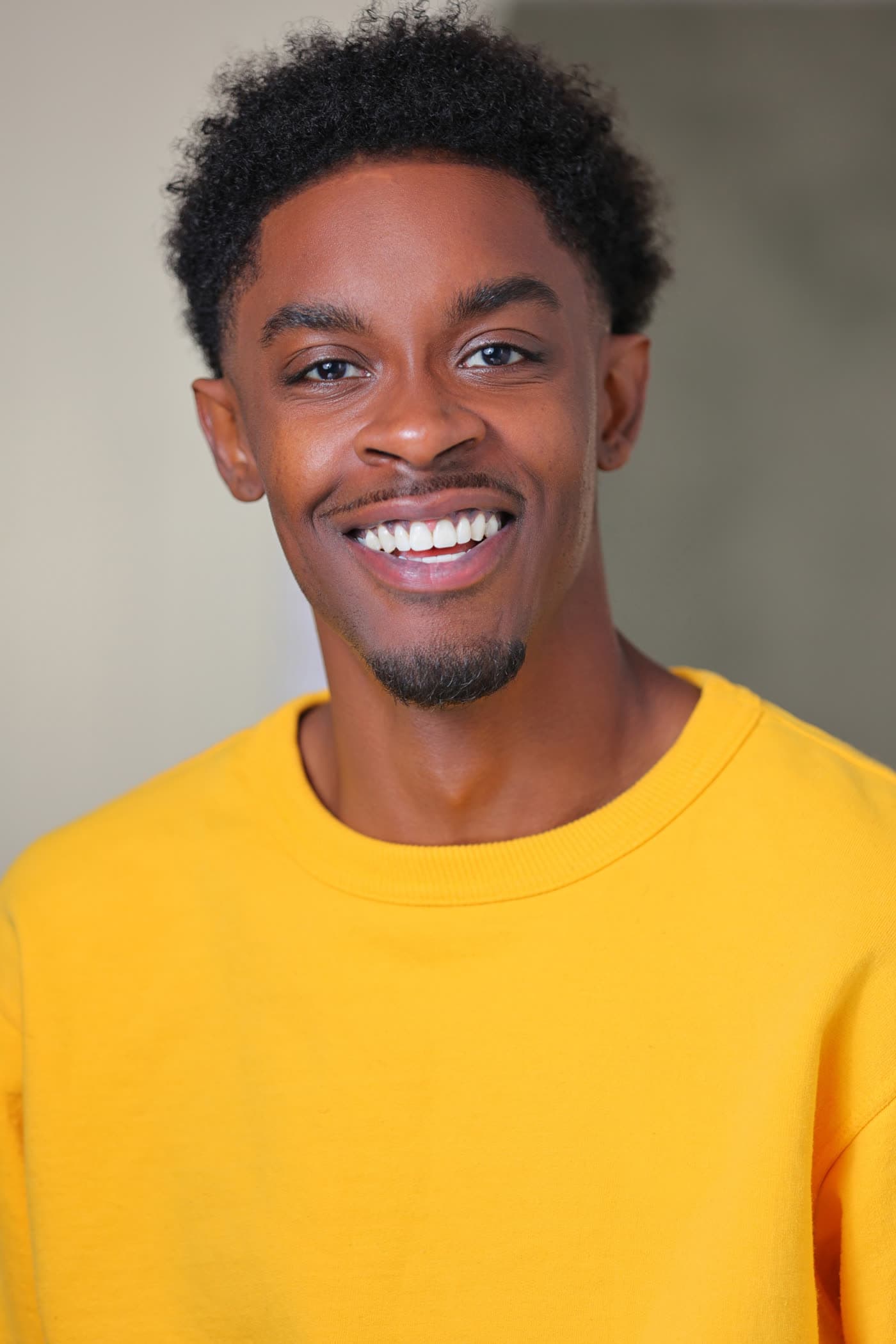 Bobby Starr, actor and comedian, smiling in a yellow sweatshirt