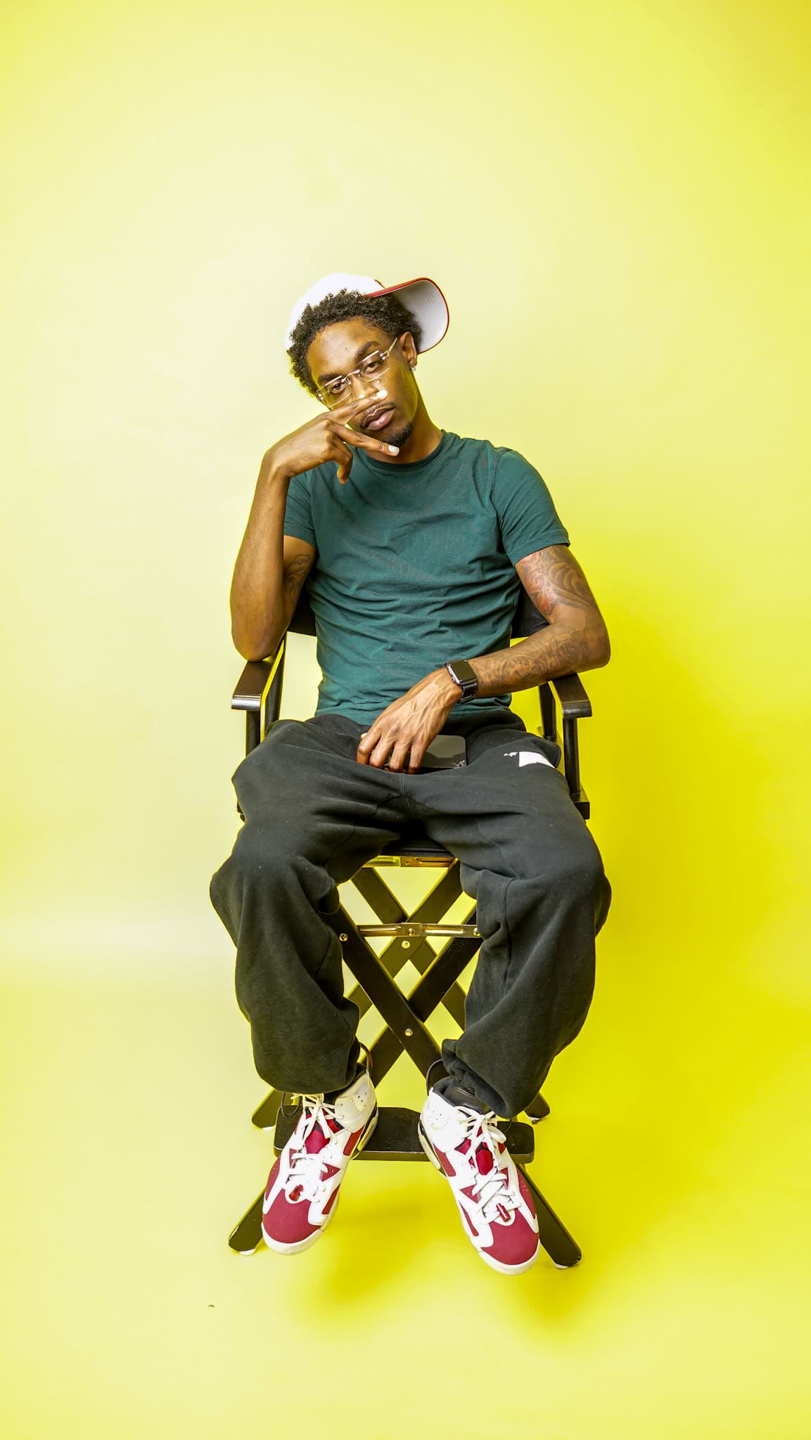 Bobby Starr seated in a director's chair on a yellow backdrop